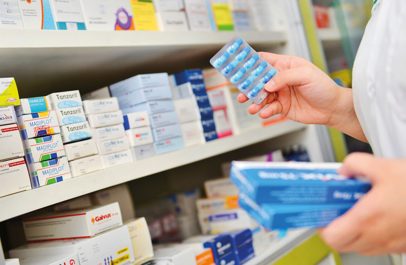 Pharmacist holding medicine box and capsule pack in pharmacy dru